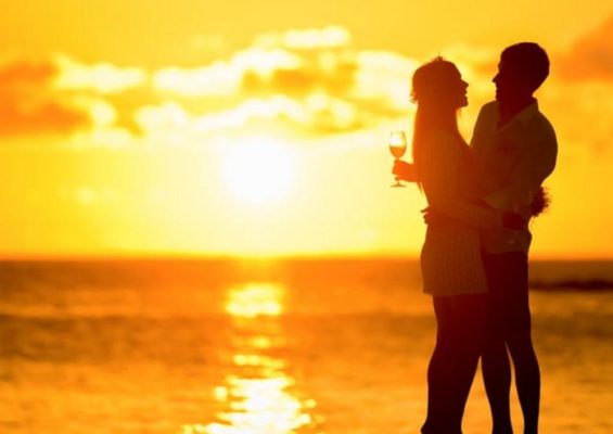 A couple hugging against the background of a setting sun.