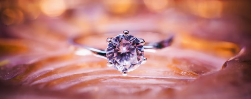 A focus of a round cut diamond engagement ring placed on a silky surface
