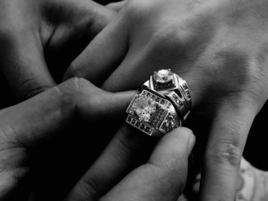 Grayscale image of a hand wearing two diamond rings