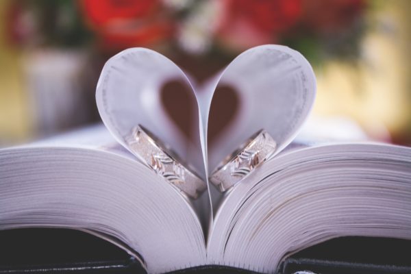 Couple ring in an open book with shape of heart