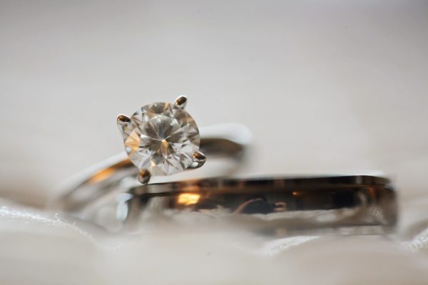 Focus view of a diamond ring in four prongs at top of a wedding band in blur