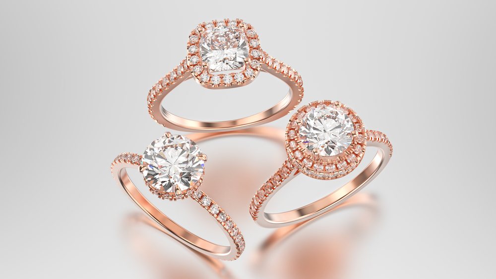 Three rose gold rings in cushion cut halo setting, round halo setting and a prong setting positioned in triangle