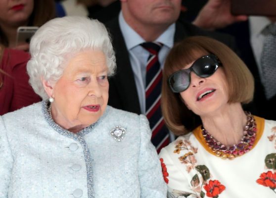 Queen Elizabeth wearing a baby blue coat with cullinan diamond brooch talking to another woman wearing an sunglasses