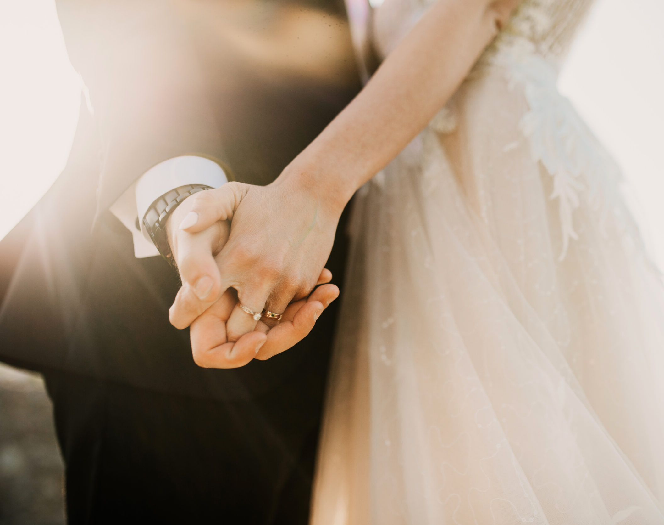 Man and Women holding hands showcasing an engagement ring